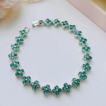 Браслет-теннис с зелёными кубическими цирконами и четырёхлистным клевером из хирургической стали